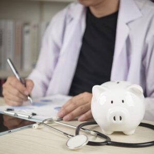 Doctor,With,Stethoscope,And,White,Piggy,Bank,On,Desk,,Concepts Frais de santé : le reste à charge annuel augmente en octobre 2026