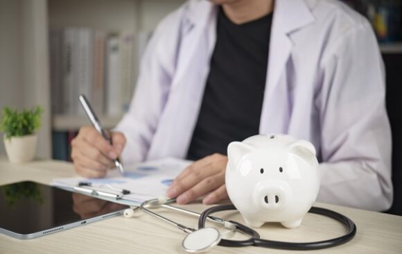 Doctor,With,Stethoscope,And,White,Piggy,Bank,On,Desk,,Concepts Frais de santé : le reste à charge annuel augmente en octobre 2026