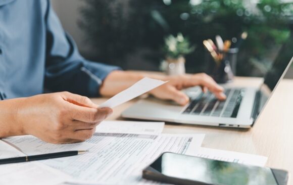 Tax,Preparation,At,Office,Desk,With,Hands,Holding,Receipt,And Impôt sur le revenu : remboursements ou prélèvements à venir