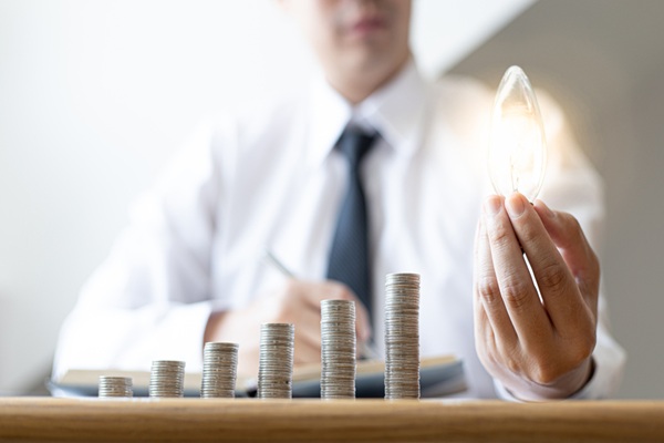 Young,Businessman,Holding,A,Light,Bulb,And,Coins,Or,Money TVA sur les cadeaux : tout est question de contrepartie