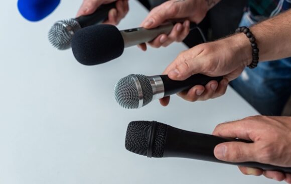 Close-up,Of,Four,Hands,Holding,Different,Microphones,,Suggesting,A,Press Facturation électronique : une tolérance pour les intermédiaires de presse ?