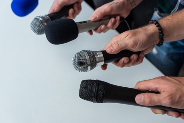 Close-up,Of,Four,Hands,Holding,Different,Microphones,,Suggesting,A,Press Facturation électronique : une tolérance pour les intermédiaires de presse ?