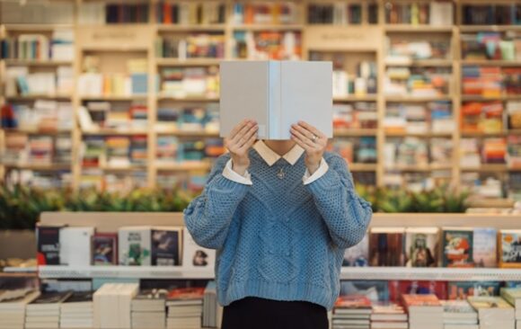 A,Young,Woman,Holds,A,Book,In,Front,Of,Her Artistes-auteurs : quelle fiscalité pour la vente de leurs propres livres ?