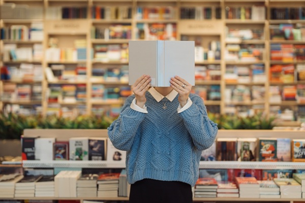 A,Young,Woman,Holds,A,Book,In,Front,Of,Her Artistes-auteurs : quelle fiscalité pour la vente de leurs propres livres ?